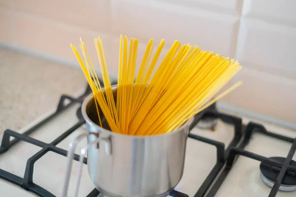 Špagety vařené v pánvi ve vařící vodě na sporáku v kuchyni — Stock fotografie