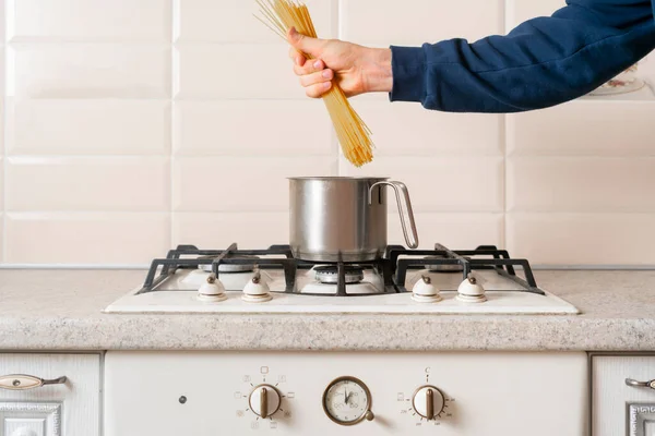 De handen met een bos rauwe spaghetti en kook het. Italiaanse noedelpasta traditioneel — Stockfoto