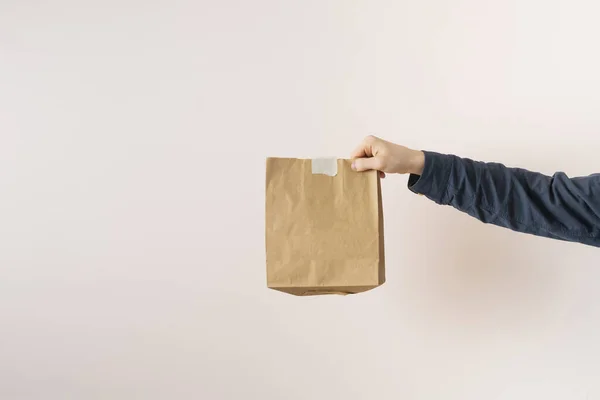 Una mano sostenga un paquete de papel con los alimentos entregados a casa — Foto de Stock