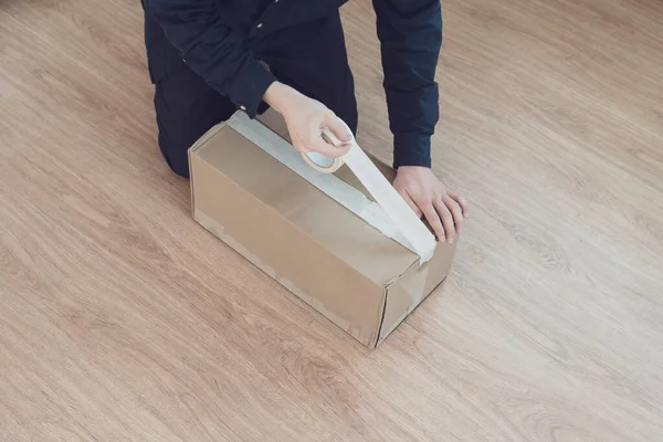 Ένα άτομο που κρατά μια ταινία και ένα κιβώτιο για να συσκευάσει το χαρτόνι, να στείλει και να παραδώσει τη ναυτιλία — Φωτογραφία Αρχείου