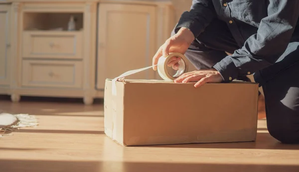 Человек, держащий ленту и коробку для упаковки картона, отправки и доставки — стоковое фото