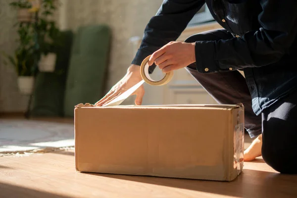 Человек, держащий ленту и коробку для упаковки картона, отправки и доставки — стоковое фото