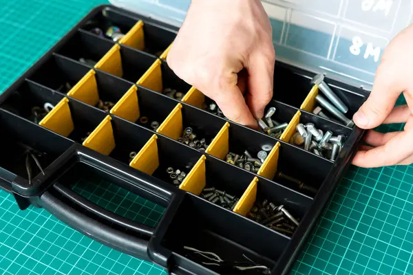Una caja de herramientas con celdas con tornillos, anclas, clavos, pernos y otras herramientas en el taller — Foto de Stock