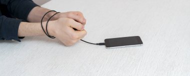 Dijital cep telefonu cihazına bağımlı bir kişi ellerini kollarına bağlar.