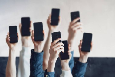 Geniş bir grup insan dijital telefon cihazını, bir sürü insan elini tutuyor.