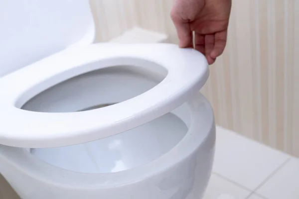 A hand open the toilet lid, home household sanitary — Stok Foto