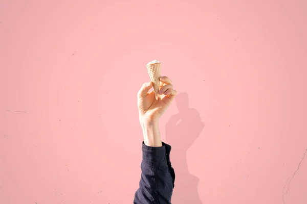 Emberi kéz kezében fagylalt kúp elszigetelt színes pasztell háttér, elvont kreatív ötlet — Stock Fotó