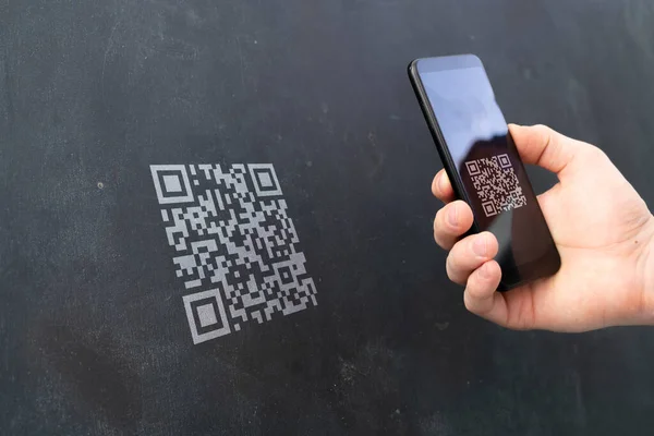 Eine Hand hält ein Smartphone und scannt den QR-Code, um eine Zahlung zu tätigen — Stockfoto