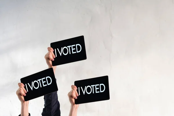 A person with a raised hand with black plate and text "i voted", democracy election — Stock Photo, Image