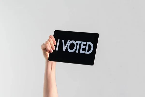 A person with a raised hand with black plate and text "i voted", democracy election — стоковое фото