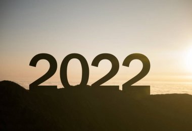 Yeni başarı ve fırsatların sembolü olan 2022 yılbaşı tabelası dağın tepesinde gün batımıyla birlikte.