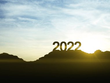 Yeni başarı ve fırsatların sembolü olan 2022 yılbaşı tabelası dağın tepesinde gün batımıyla birlikte.