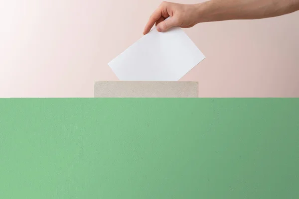 Een kiezer hand zet papier in de urn, democratie verkiezing — Stockfoto