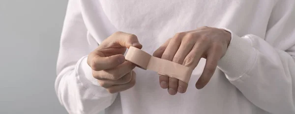 Una aplicación de cinta médica en la mano, yeso de protección contra el dolor en la piel — Foto de Stock