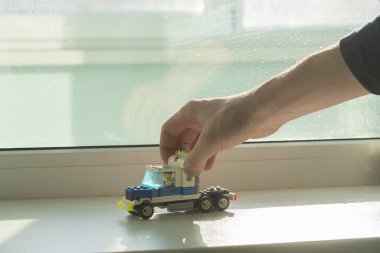 Oyuncak araba yapımcısını tutan bir el, detaylardan, tuğlalardan, yaratıcılıktan ve öğrenmeden oluşur.