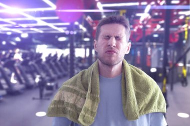 Egzersizden sonra spor salonunda havlu kullanan yorgun bir adam.