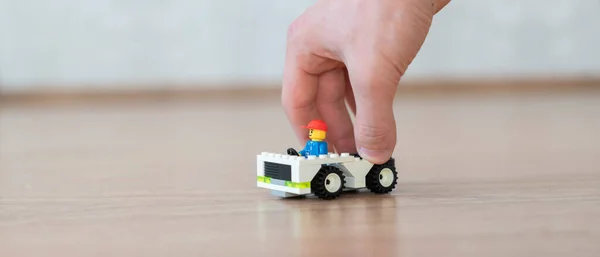 おもちゃの車のコンストラクタを持っている手は、細部のレンガ、創造性と学習で作られました — ストック写真