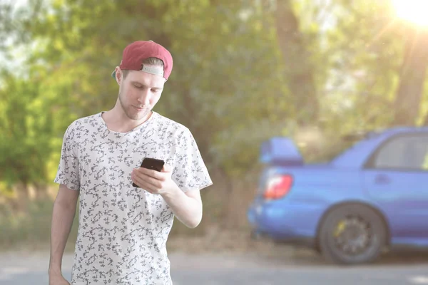 Henkilö, jolla on älypuhelin ja joka lataa sähköauton akkua — kuvapankkivalokuva
