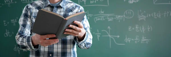 Un joven profesor en la universidad sosteniendo un libro en el aula — Foto de Stock