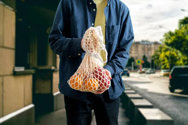 Osoba trzymająca siatkową eko-torbę ze świeżą żywnością owocową ze sklepu spożywczego — Zdjęcie stockowe