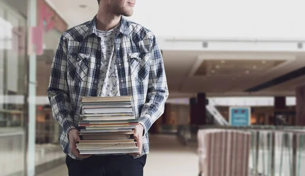 Um estudante segurando pilha de livros, carregar livros didáticos de papel pesado, conceito de motivação — Fotografia de Stock