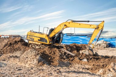 Kazıcı buldozer toprak kazıyor, inşaat alanını kürekliyor.