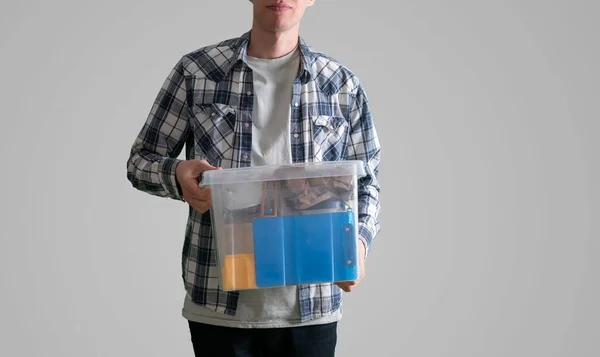 İçinde eşyalar olan plastik bir kutu taşıyan genç bir adam. — Stok fotoğraf