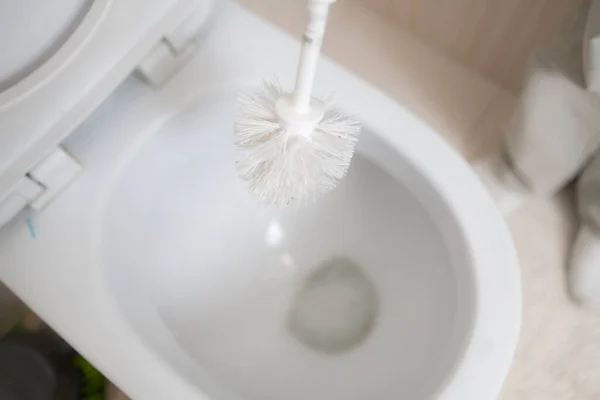 A hand holding a brush scrub and cleaning the toilet — Stock Photo, Image