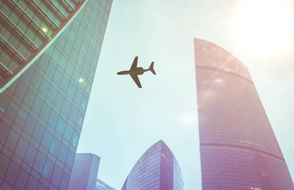 A looking at the sky with the silhouette of flying plain over the city — Stockfoto