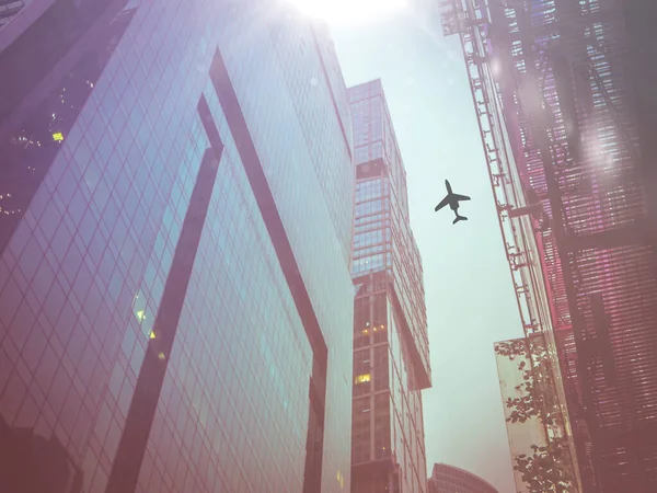 A looking at the sky with the silhouette of flying plain over the city — Stockfoto