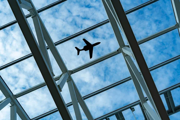 A looking at the sky with the silhouette of flying plain over the city — Stockfoto