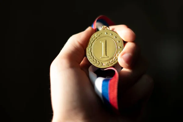 Mão dos campeões segurando uma medalha de ouro, conceito de sorte vencedor simples — Fotografia de Stock