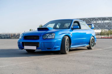 Modern, hızlı, mavi yarış arabası yaz antrenmanı gününde pistte.