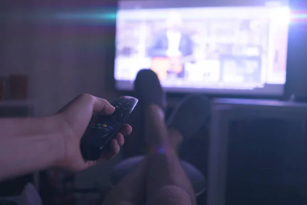 Een persoon die thuis ligt en tv kijkt, benen op tafel legt, geniet en ontspant — Stockfoto
