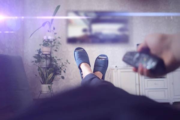 A person lying at home and watch tv, put legs on the table, enjoy and relax — Stockfoto