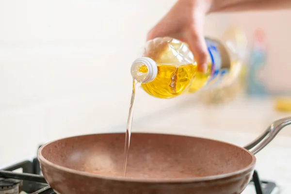 Een vrouw hand giet bakolie op de pan thuis — Stockfoto