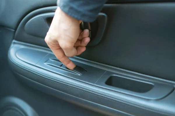 Uma pessoa sentada dentro do carro e abrir a janela, dedo apertar o botão — Fotografia de Stock