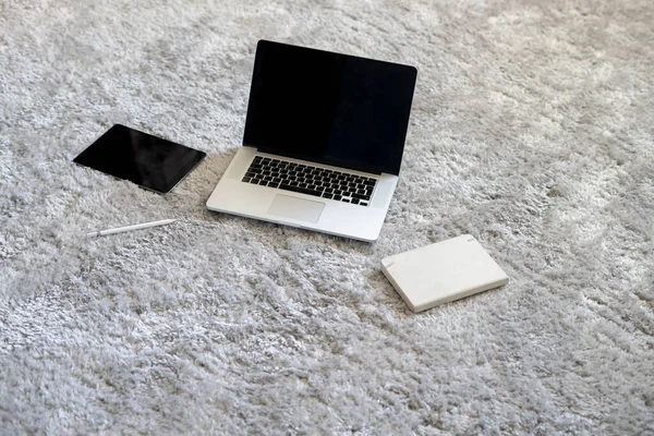 A laptop and other devices on the floor on the soft carpet in living room at home, isolation during coronavirus pandemy — Foto de Stock