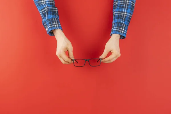 Una mano sosteniendo gafas negras aisladas contra el fondo colorido, minimalismo concepto simple — Foto de Stock