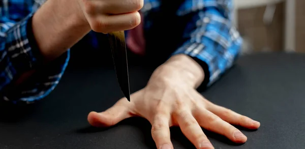 Mano con cuchillo golpeando entre los dedos en la mesa, jugando el juego con una hoja afilada banner web ancha — Foto de Stock