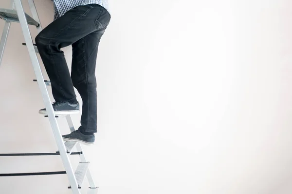 A close up workers feet on the ladder climb to the top against the wall with copy space — Stockfoto