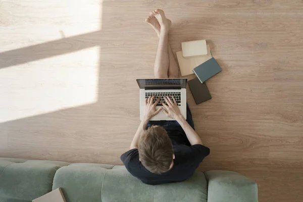 Górny widok osoby męskiej leżącej na podłodze i pracującej na laptopie podczas pandemii covid-19, odległość pracy online — Zdjęcie stockowe