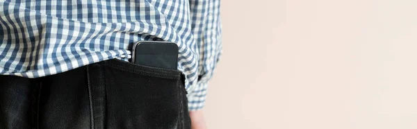 En närbild smartphone inuti fickan av manliga kläder, bakåtsikt, som symbol för hälsoeffekter från mobiltelefon — Stockfoto