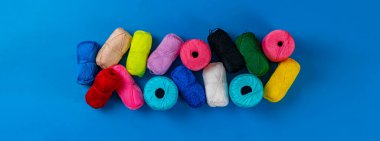 Örgü örmek için farklı renklerde iplikler örüyorlar, yukarıdan ağ için uzun bir afiş görüyorlar.