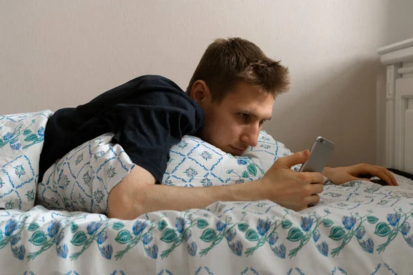 Egy férfi hazudik és okostelefont használ alvás előtt, este az ágyhálózatban függőség — Stock Fotó