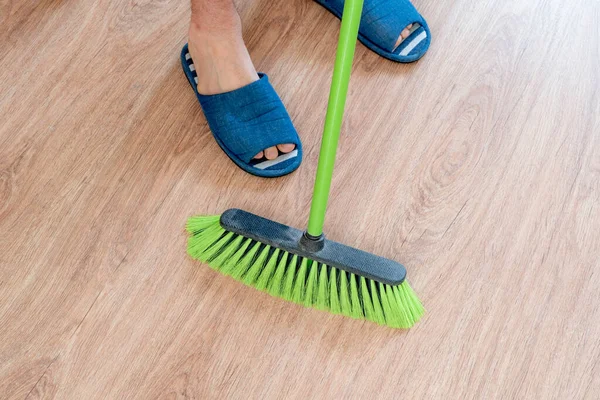 Une personne de près tenant une brosse et nettoyant le sol avec une brosse à la maison — Photo