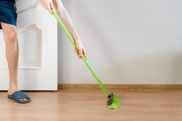 Una persona cercana sosteniendo un cepillo y limpiando el suelo con un cepillo en casa — Foto de Stock