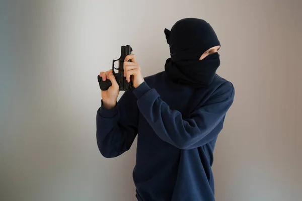 Una persona masculina irreconocible en la máscara negra y pistola, proscrito y el concepto del crimen —  Fotos de Stock