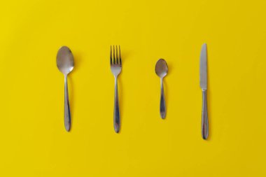 Mutfak gereçleri çatal, bıçak, kaşık ve çatal renkli masaya saçılmış.