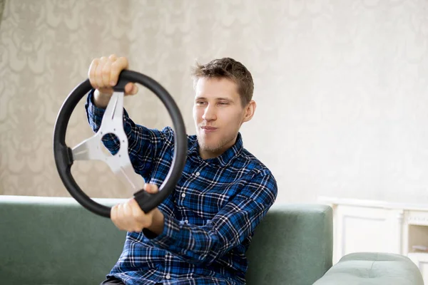 En ung man hålla en ratt och föreställa sig själv som en racerförare — Stockfoto